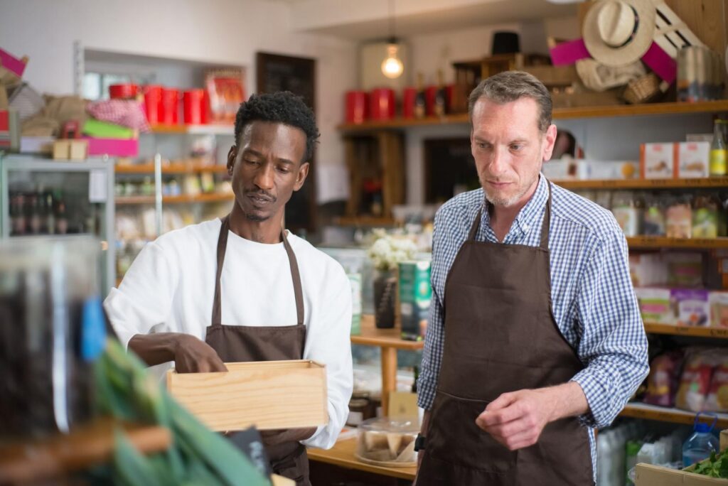 Two shopkeepers stocking shelves in a neighborhood store