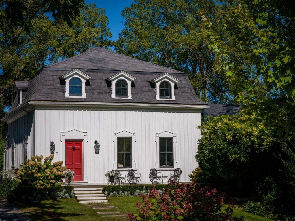 White house with a red front door and a garden